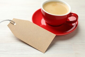 Blank card and cup of coffee on white wooden table, closeup. Mockup for design