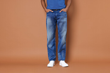 Naklejka premium Man wearing stylish jeans on brown background, closeup