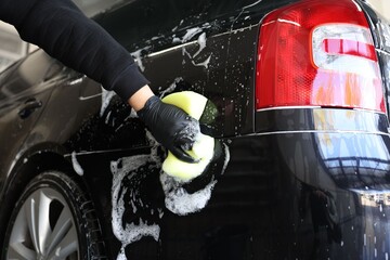 Man washing auto with sponge at car wash, closeup