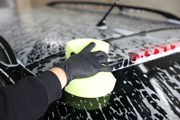 Man washing auto with sponge at car wash, closeup
