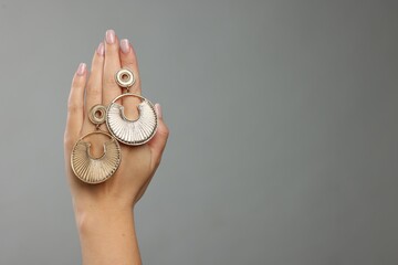 Woman with stylish earrings on grey background, closeup. Space for text