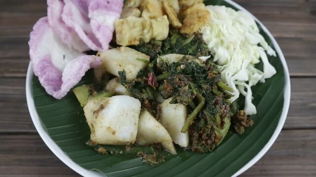 a traditional Indonesian dish, pecel or lotek served on a plate lined with a fresh green banana leaf