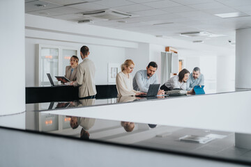 A group of office teammates gathers along a sleek railing in a bright, contemporary lobby,...