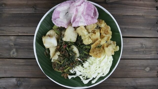 a traditional Indonesian dish, pecel or lotek served on a plate lined with a fresh green banana leaf