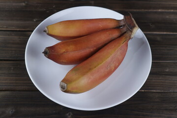fresh raw red banana on white plate