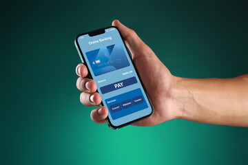 Online payment. Man holding mobile phone with open app in hand on teal background, closeup