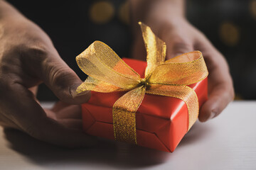 Man holding Christmas gift by wooden table