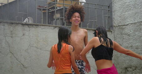 Laughing children of diverse ethnicities playing under water spray, holding hands and spinning in...