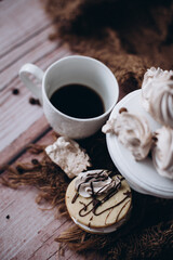 Cup of coffe with cookies and meringues on rustic wooden tabel