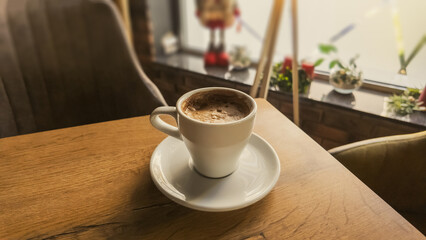 Cup of hot coffee on wooden table in cozy café, warm morning light creating peaceful atmosphere and inviting lifestyle scene