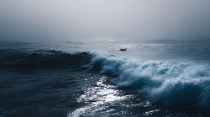 Fototapeta premium A solitary dolphin or surfer navigates the vast foggy ocean with powerful waves breaking in the foreground under a moody atmosphere