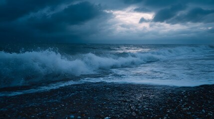 A dramatic dark blue ocean with crashing waves on a pebble shore at dusk under stormy clouds