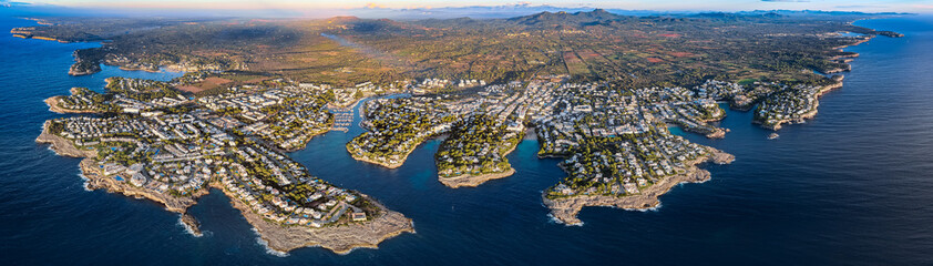 Fototapeta premium Aerial Sunrise Over Cala d'Or: Multiple Coves, Yachts, and Resort Town on Mallorca's Coast