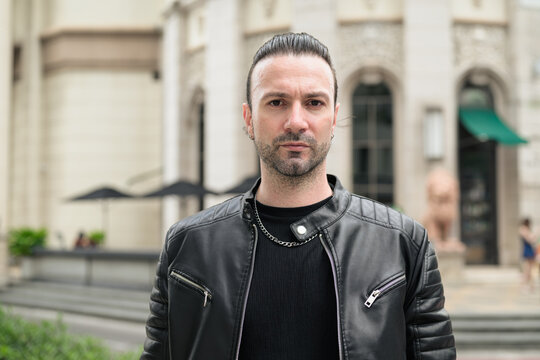 Fototapeta Handsome bearded man in black leather jacket posing in city streets