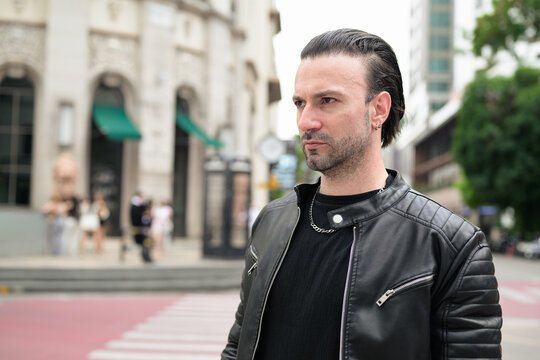 Fototapeta Handsome bearded man in black leather jacket posing in city streets