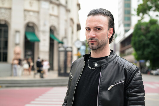 Fototapeta Handsome bearded man in black leather jacket posing in city streets
