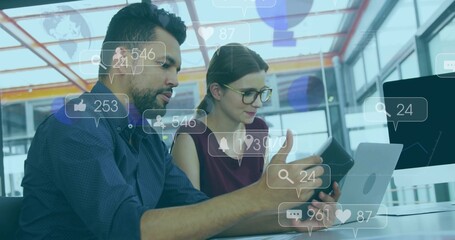 Collaborating coworkers analyzing social media engagement at modern office desk, with tablet laptop