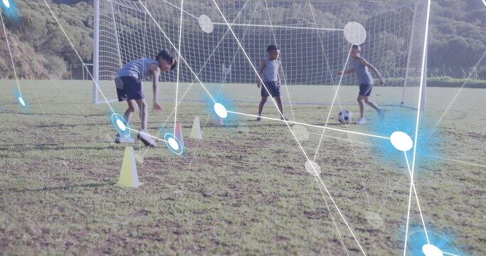 Practicing three boys dribbling soccer ball through yellow cones on pitch, by goal netting
