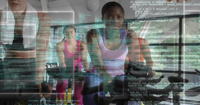 Black woman wearing lavender top, black shorts, cycling on exercise bikes in gym with code overlay - Powered by Adobe