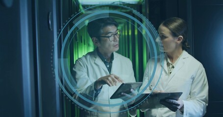 Discussing engineers in labcoats sharing data in data center aisle, with tablet and digital overlay