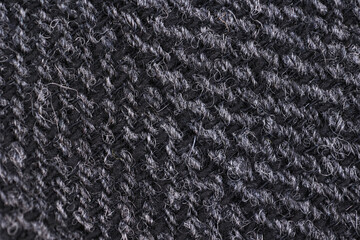 Extreme close-up macro shot of dark gray English tweed wool fabric. Shows the classic herringbone weave texture, natural fibers, and soft, durable textile material. Ideal for fashion and tailoring. © Sceliano
