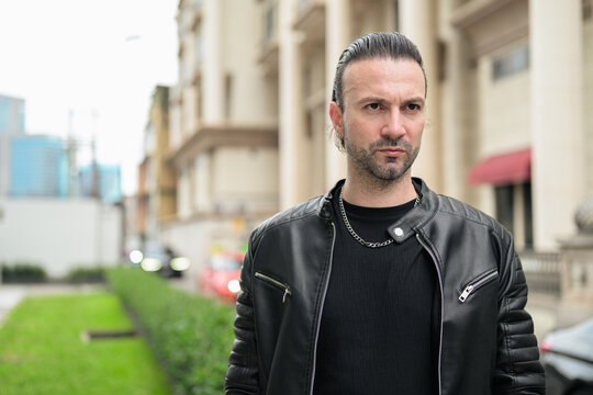 Fototapeta Handsome bearded man in black leather jacket posing in city streets