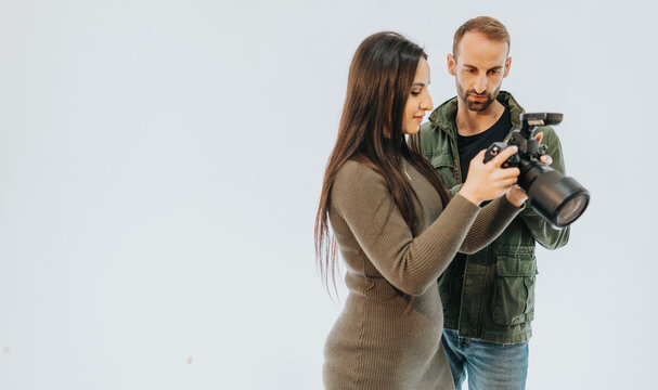 A man and woman observe and discuss a camera in a professional setting, emphasizing a collaborative and instructional atmosphere.