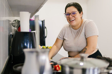 Colombian woman smiling and cooking a family meal in a modern kitchen