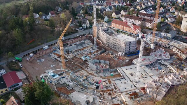 Aerial view of a multi-building residential construction site in Stein, near Nuremberg, Germany. Heavy machinery, cranes, and modular foundations highlight the role of housing and the EU economy.