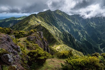 Fototapeta premium Majestic mountain landscape with lush green slopes, dramatic clouds, rolling hills, and rocky foreground enhancing nature's awe-inspiring beauty. Perfect for outdoor enthusiasts and travel lovers