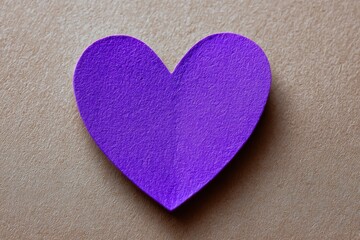 Purple paper heart on light brown textured surface, classic shape with rounded top and pointed bottom, unique paper texture adds visual interest for romantic and creative projects