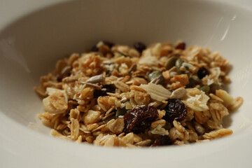 Granola cereal with oats, nuts, and dried fruits filling a white bowl. Cotswolds countryside, England