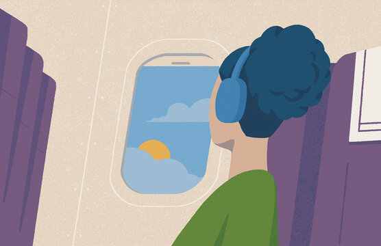 Woman listening to headphones looking out of plane window