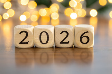Wooden blocks forming “2026” on reflective surface with festive bokeh lights—minimal yet celebratory scene marking a new year with warmth and quiet charm. generative ai
