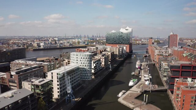 A smooth aerial shot of Hamburg&rsquo;s HafenCity with its waterfront architecture and the iconic Elbphilharmonie concert hall in the distance, highlighting city redevelopment and cultural growth.