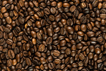 Macro image of roasted coffee beans forming a dense, textured background. The glossy brown tones and natural variations highlight freshness and rich aroma.