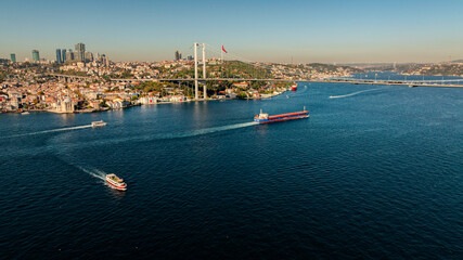 Aerial view of the Bosphorus Bridge with drone on a cloudy day. Tanker ship passing under the FSM Bridge with a heavy car traffic on the bridge.Aerial view of The Second Bosphorus Bridge.
