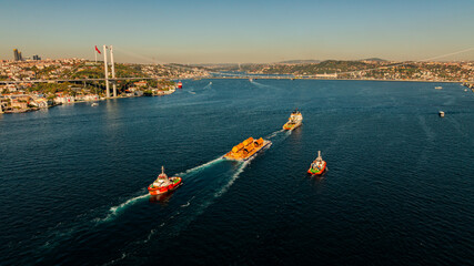 Aerial view of the Bosphorus Bridge with drone on a cloudy day. Tanker ship passing under the FSM Bridge with a heavy car traffic on the bridge.Aerial view of The Second Bosphorus Bridge.