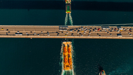 Aerial view of the Bosphorus Bridge with drone on a cloudy day. Tanker ship passing under the FSM Bridge with a heavy car traffic on the bridge.Aerial view of The Second Bosphorus Bridge.