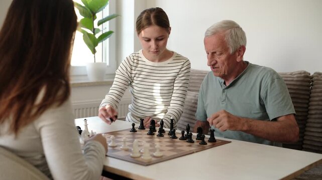 Grandfather Playing Chess With Granddaughters At Home