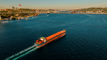 Aerial view of the Bosphorus Bridge with drone on a cloudy day. Tanker ship passing under the FSM Bridge with a heavy car traffic on the bridge.Aerial view of The Second Bosphorus Bridge.