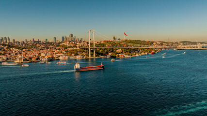 Aerial view of the Bosphorus Bridge with drone on a cloudy day. Tanker ship passing under the FSM Bridge with a heavy car traffic on the bridge.Aerial view of The Second Bosphorus Bridge.