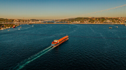 Aerial view of the Bosphorus Bridge with drone on a cloudy day. Tanker ship passing under the FSM Bridge with a heavy car traffic on the bridge.Aerial view of The Second Bosphorus Bridge.