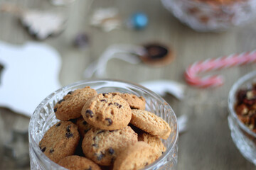 Various Christmas decorations, cookies, chocolate and nuts on wooden background. Selective focus.