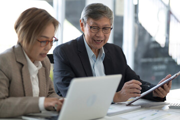Asian business professionals discuss project collaborate office setting sharing ideas using laptop tablet for corporate strategy financial data analysis