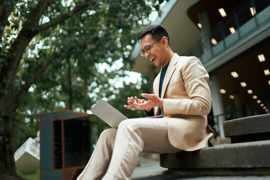 Businessman enjoying remote work outdoors and laughing deeply