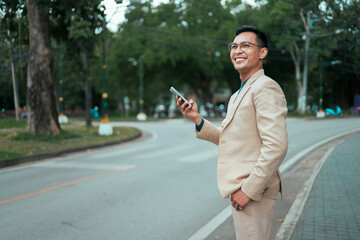 Asian businessman using smartphone smiling on city street