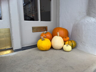 Several different sized and coloured pumpkins have been placed outside a doorway as decoration for Halloween