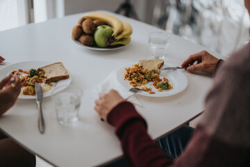 Close up view of a shared breakfast table featuring healthy foods and individuals enjoying their meal. This scene portrays a cozy and domestic atmosphere with an emphasis on nutrition and togetherness