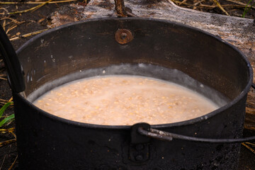 Cooking oatmeal over an open fire in a rustic setting in Russia